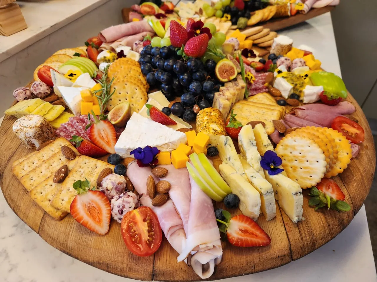 A loaded charcuterie and cheese board with fruit and crackers.